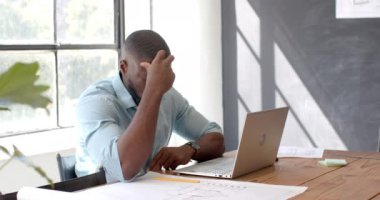 Hüsrana uğramış işadamı dizüstü bilgisayarda çalışıyor ve ofisin planlarını inceliyor. stres, profesyonel, planlama, mimari, tasarım