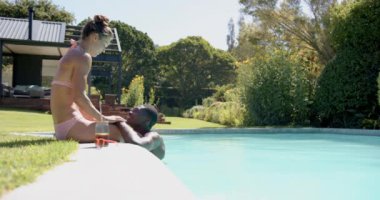 Havuz başında rahatlayan, çeşitli çiftler arka bahçede güneşli bir günün tadını çıkarıyorlar, fotokopi odası. Rahatlama, rahatlama, güneş ışığı, yaz mevsimi, arkadaşlık, sükunet.