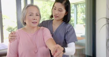 Fizyoterapist, evde kol egzersizleri yapan yaşlı Asyalı kadına yardım ediyor. Fizyoterapi, rehabilitasyon, sağlık, sağlık, yaşlılık, destek
