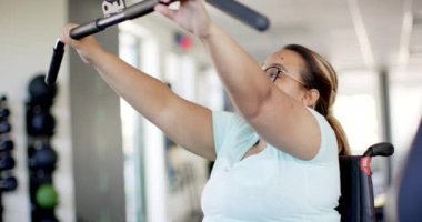 Tekerlekli sandalyede felçli bir kadın rehabilitasyon salonunda kablo makinesiyle egzersiz yapıyor. egzersiz, fizik tedavi, sağlık hizmeti, dayanıklılık eğitimi, sakatlık, spor, değişmemiş, yavaş çekim