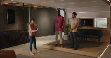 Fikirleri sunmak, iki erkek ofiste dikkatle dinlerken bir kadının el kol hareketi yapması. Takım çalışması, işbirliği, beyin fırtınası, iş toplantısı, iletişim, şirket