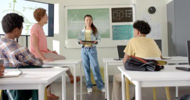 Tableti tutan ve sınıf arkadaşlarıyla konuşan, lisede sunum yapan genç bir kız. Eğitim, sunum, teknoloji, öğrenme, gençler, iletişim