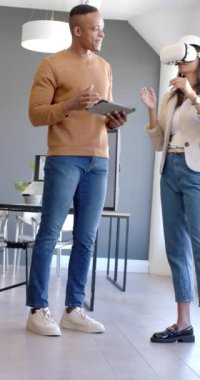 Dikey video: VR kulaklık kullanan kadın, meslektaşı ile ofisinde tablet tutarken tartışıyor. Teknoloji, yenilik, işbirliği, takım çalışması, tartışma, toplantı