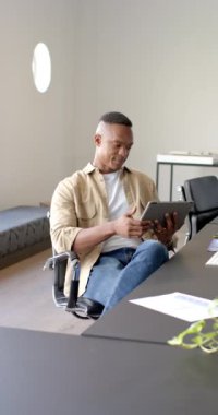 Dikey video: Ofiste oturan, tableti tutan ve kameraya güvenle bakan adam. İş, teknoloji, profesyonel, kurumsal, modern, işyeri