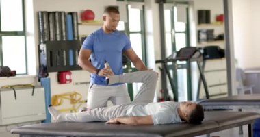 Klinikteki rehabilitasyon sırasında hastanın bacağını esneten bir fizyoterapist. Fizyoterapist, fizyoterapi, sağlık, tıbbi, terapi, iyileşme, değişmemiş, yavaş çekim