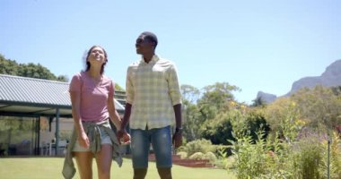 Çeşitli çiftler havuz başında oturmuş, güneşli bir günün tadını çıkarıyorlar. Kadın kahverengi saçlı, adam güneş gözlüğü takıyor, ikisi de günlük yaz kıyafetleri içinde, değişmemiş, ağır çekimde.