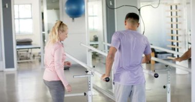 Fizik tedavi merkezinde terapistle paralel barlar kullanan bir adam. fizyoterapi, sağlık, iyileşme, egzersiz, tıbbi, tedavi, değiştirilmemiş, yavaş çekim