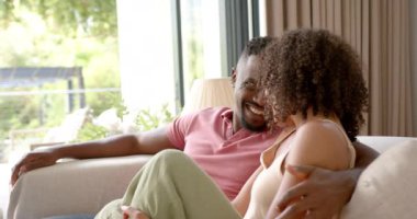 Kanepede oturan gülümseyen bir çift, evde birlikte güzel vakit geçiriyorlar. Rahatlama, birliktelik, bağlanma, evcil, boş zaman, mutluluk