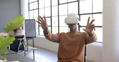 VR kulaklık kullanarak, Afrikalı Amerikalı adam modern ofisteki sanal arayüzle etkileşime geçiyor. Teknoloji, yenilik, sanal gerçeklik, etkileşim, dijital, fütürist