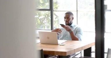 Akıllı telefon ve dizüstü bilgisayar kullanan, ofis masasında çalışan, birden fazla iş yapan bir adam. İş, teknoloji, üretkenlik, çalışma alanı, profesyonel, aygıtlar