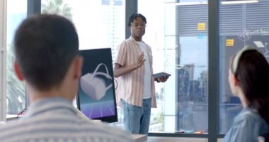 Projeyi sunmak, elinde tablet olan adam ve ofisteki meslektaşlarına verileri açıklamak. İş, takım çalışması, sunum, toplantı, işbirliği, şirket