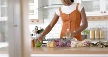 Sebze ve şişeleri boşaltan kadın, mutfakta erzak hazırlayan kadın. Sağlıklı, yemek, ev, yaşam tarzı, taze, yerli