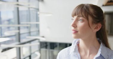 Modern ofis binasının penceresinden bakan gülümseyen kadın, ilham aldığını hissediyor. İş, ilham, kurumsal, profesyonel, düşünce, motivasyon