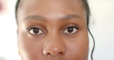 Kahverengi gözlü genç bir Afro-Amerikalı kadın evinde, evinde dört gözle bekliyor. Temiz bir cildi var, çok az makyaj yapıyor, ve saçları arkaya çekilmiş, değişmemiş, yavaş çekim..