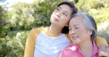 Gülümseyen Asyalı kadın dışarıda yaşlı Asyalı kadını kucaklıyor, birlikte güzel vakit geçiriyorlar. Aile, bağ, mutluluk, çok nesilli, birliktelik, bağlantı