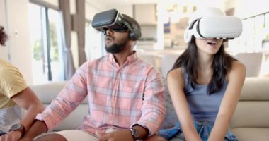 Evde, VR kulaklıkları kullanarak, farklı arkadaşlar koltukta sanal gerçeklik oyununun keyfini çıkarıyorlar. Teknoloji, eğlence, eğlence, sürükleyici, rahatlama, rahatlama