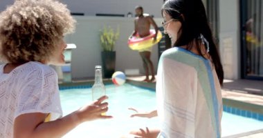 Çeşitli arkadaşlar havuz başında tezahürat yapıyor, adam şişme yüzükle atlıyor, yaz partisinin tadını çıkarıyor. Kutlama, eğlence, havuz kenarı, toplanma, su, dinlenme