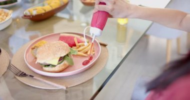 Patates kızartmasına ketçap sıkmak, çeşitli arkadaşlarla hamburger ve patates kızartması yemek. Yemek, yemek, fast food, sosyalleşme, yemek, keyif