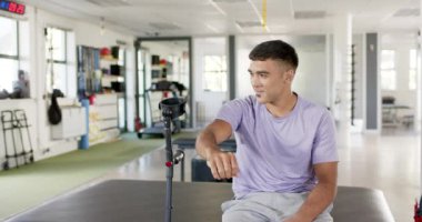 Rehabilitasyon merkezinde koltuk değnekleriyle oturan, gülümseyen ve mutlu görünen bir adam. İyileşme, sağlık, iyileşme, fizik tedavi, destek, güç, değişmemiş, yavaş çekim