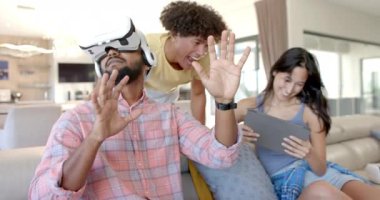 VR kulaklığı kullanarak, adam sanal dünyayla etkileşime geçiyor, çeşitli arkadaşlar izliyor ve gülüyor. Teknoloji, sanal gerçeklik, oyun, eğlence, etkileşim, kahkaha