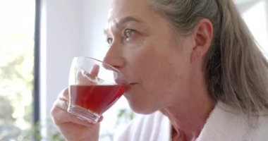 Evde dinlenen, rahat bir ortamda çay içen olgun bir kadın. Rahatlama, rahatlama, rahatlık, yaşam tarzı, kapalı mekanlar, hygge, içecek, değiştirilmemiş, yavaş çekim