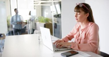 Bilgisayarda daktilo etmek, modern ofiste çalışan akıllı telefon ve bir bardak suyla çalışan bir kadın, kopyalama alanı. İş, işyeri, teknoloji, kadın, üretkenlik, çoklu görev