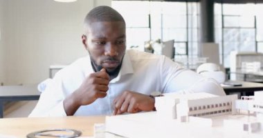 Ofisteki bina modelini inceleyen mimar tasarım detaylarına odaklanıyor. Mimarlık, planlama, inşaat, profesyonel, iç mimari