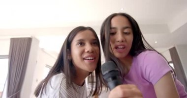 Karaoke yapan, gülümseyen ve eğlenen iki genç kız. Müzik, eğlence, arkadaşlık, eğlence, mikrofon, eğlence.