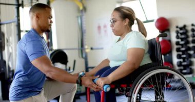 Fizyoterapist, tekerlekli sandalyedeki belden aşağısı felçli kadına spor salonunda halterli egzersiz yaptırıyor. Rehabilitasyon, fizyoterapi, sağlık, iyileşme, uygunluk, destek, değişmemiş, yavaş çekim