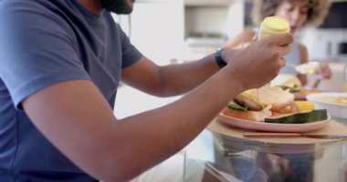 Hamburgere hardal eklemek, masadaki farklı arkadaşlarla yemek yemek. Yemek, yemek, öğle yemeği, eğlence, toplanma