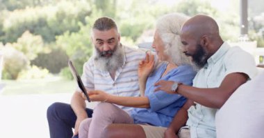 Son sınıf arkadaşları kanepede otururken tableti gösterip gülüyorlar. Yaşlılar, dostluk, teknoloji, kahkaha, oturma odası, rahatlama