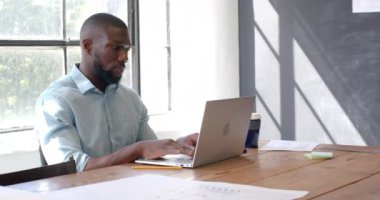 Dizüstü bilgisayarda çalışan, ofiste çalışan, masadaki belgeleri düşünen ve analiz eden bir adam. İş, işyeri, profesyonel, strateji, planlama, odaklanma