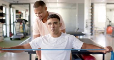 Fizik tedaviye yardım etmek, engelli bir adamın direniş bandı kullanması. Rehabilitasyon, sağlık hizmeti, fizyoterapi, egzersiz, fitness, eğitim, değişmemiş, yavaş çekim