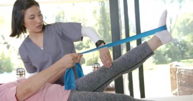 Fizyoterapist, evdeki direniş bandı egzersizlerinde kıdemlilere yardımcı oluyor. Rehabilitasyon, terapi, fitness, sağlık, egzersiz, destek