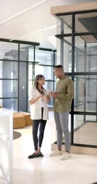 Dikey video: İş konuşmak, modern ofis ortamında akıllı telefona bakan meslektaşlar. İş, takım çalışması, işbirliği, teknoloji, cihaz, beyin fırtınası