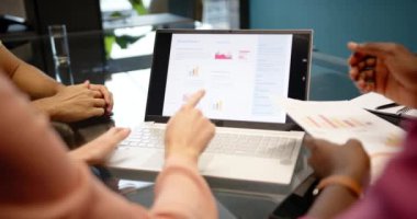 Laptop ekranını işaret eden çeşitli meslektaşlar yıllık raporlarını ofis toplantısında tartışıyorlar. İş, takım çalışması, işbirliği, şirket, tartışma, analiz