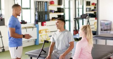 Spor salonunda rehabilitasyon seansı, engelli bir adam terapistlerle konuşuyor. Fizyoterapi, fizyoterapi, protez, iyileşme, sağlık, egzersiz, değişmemiş, yavaş çekim