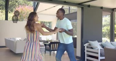 Çeşitli çiftler evlerinde güneşli bir verandada dans etmekten zevk alıyorlar. Kadın uzun, dalgalı kahverengi saçlı ve adam da basit beyaz bir tişört giyiyor, değiştirilmemiş, ağır çekimde.