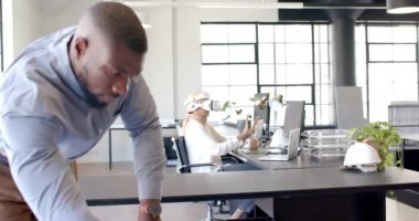 VR kulaklığı kullanan bir kadın, yanında meslektaşıyla modern ofiste masa başında çalışıyor. Teknoloji, işyeri, işbirliği, sanal gerçeklik, birlikte çalışma, yenilik