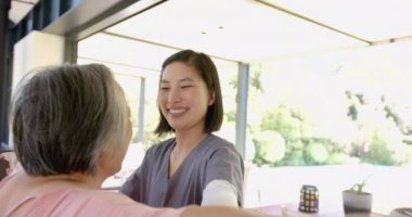 Gülümseyen bakıcı, evde fizik tedavi egzersizleri için kıdemli Asyalı kadına yardım ediyor. yaşlılar, ev bakımı, sağlık hizmetleri, yardım, rehabilitasyon, refah