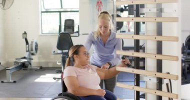 Terapistle egzersiz, tekerlekli sandalyede felçli bir kadın rehabilitasyonda ekipman kullanıyor. fizik tedavi, sağlık hizmeti, egzersiz, terapi, fitness, iyileşme, değişmemiş, yavaş çekim
