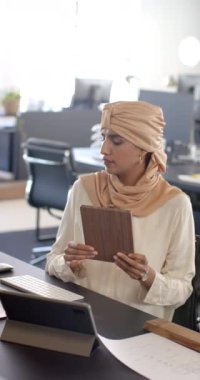 Dikey video: Tablet tutmak, ofiste masa başında çalışmaya odaklanan kadın. İş, çalışma alanı, teknoloji, şirket, konsantrasyon, profesyonel