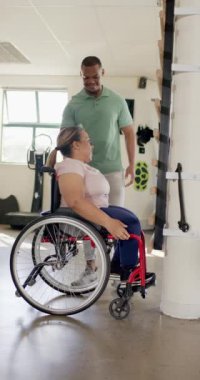 Dikey video: beşlik çakan terapist, rehabilitasyon sırasında tekerlekli sandalyede olan kadın. Fizyoterapist, fizyoterapi, sağlık, tıbbi, hareketlilik, destek