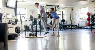 Engelli bir adama yardım etmek, paralel bar egzersizleri sırasında antrenörlük yapmak. Fizyoterapist, rehabilitasyon, fizyoterapi, denge, sağlık, tıbbi, değişmemiş, yavaş çekim