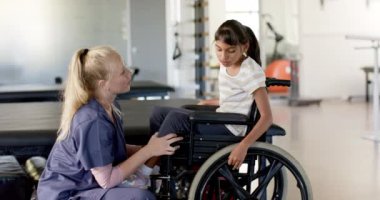 Terapi seansı sırasında tekerlekli sandalyede beyin felci geçiren bir kıza yardım eden rehabilitasyon terapisti. Sağlık, fizyoterapi, engellilik, destek, tıbbi, bakıcı, değişmemiş, yavaş çekim