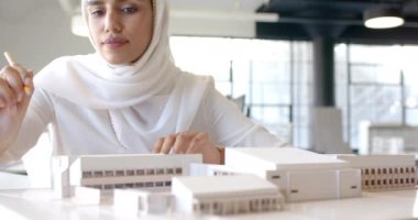 Ofisteki yapı modeli üzerinde çalışan mimar, tasarım detaylarına odaklanıyor, kopyalama alanı. Mimarlık, planlama, taslak, inşaat, yaratıcılık, profesyonel