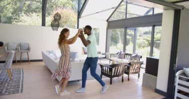 Birlikte dans eden, çeşitli çiftler geniş pencereli modern oturma odasında eğleniyorlar. Dans, ev, eğlence, yaşam tarzı, çağdaş, neşeli