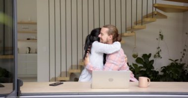 Çift ırklı genç bir kadın ve beyaz bir genç adam evde dizüstü bilgisayarlarıyla oturuyorlar. Minimalist bir tasarımı olan modern bir evdeler ve arka planda bir merdiven var, değiştirilmemiş, yavaş çekimde.