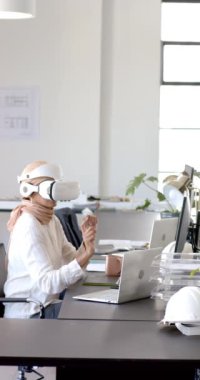 Dikey video: VR kulaklık kullanan kadın, modern ofisteki sanal içerikle etkileşim içinde. Sanal gerçeklik, teknoloji, yenilik, etkileşimli, bağlılık, çalışma alanı