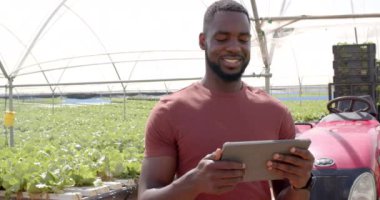 Gülümseyen çiftçi hidrofonik çiftlikte tablet tutuyor, ürünleri dijital olarak yönetiyor. Tarım, teknoloji, tarım, bahçıvanlık, yenilik, üretim